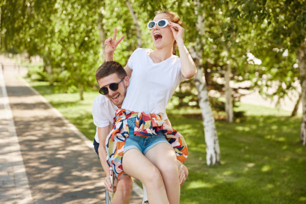 couple heureux amoureux à vélo. beau mec et jeune femme sensuelle date. des jeunes qui s’amusent sur la nature, dans le parc. - women love heterosexual couple color image photos et images de collection