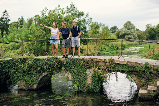 Three teenage kids enjoying summer vacations in Cotswolds, Gloucestershire, United Kingdom. 
They are standing on the bridge over the river in Bibury.
Shot with Canon R5