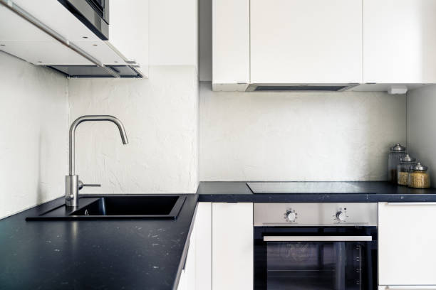 istock Kitchen interior. Modern white and black design. Scandinavian minimalist lifestyle. Induction cooker and stove, electric oven in new apartment. Contemporary faucet and sink. 1667989593