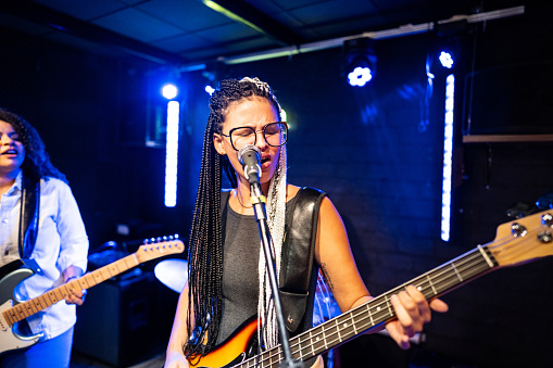 Young woman singing and playing bass on a show