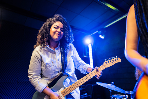 Portrait of a mid adult woman playing electric guitar on a show