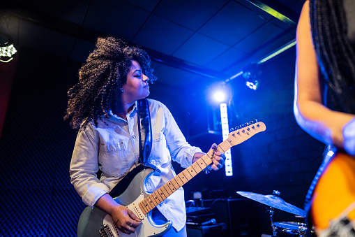 Mid adult woman playing electric guitar on a show