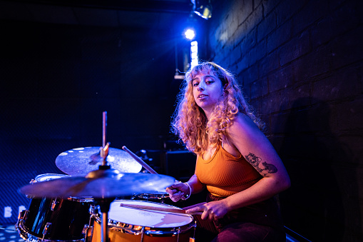 Portrait of a young woman playing drum kit on a show
