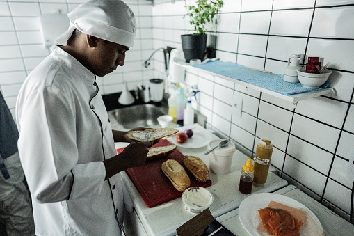 Chef young man making a sandwich on a commercial kitchen