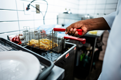 Close-up of a man frying fries on a commercial kitchen