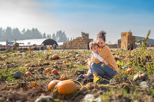 istock Mother and young daughter hug while at a pumpkin patch 1668007613