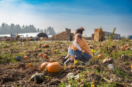 istock Mother and young daughter hug while at a pumpkin patch 1668007614