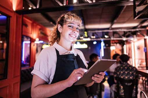 Portrait of a waitress young woman using digital tablet on a restaurant