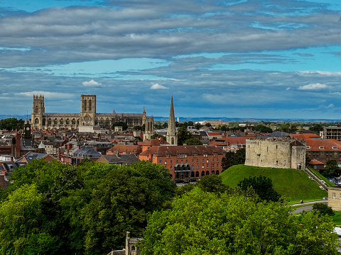An aerial Photograph of York Minster, Clifford’s Tower Castle with a church spire in between both important monuments, in York, North Yorkshire, England. The photograph was produced on a bright sunny afternoon