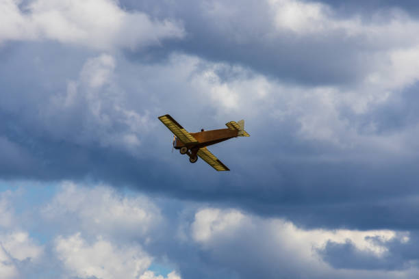 Old historic biplane fly on cloudy sky from side