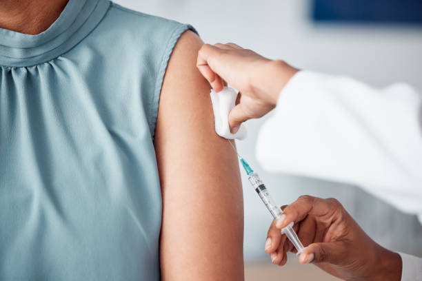 Hands, medical and doctor with patient for vaccine in a clinic for healthcare treatment for prevention. Closeup of a nurse doing a vaccination injection with a needle syringe in a medicare hospital. stock photo