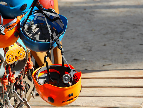 Climbing equipment - colorful helmets hanging on a board in a rope park.