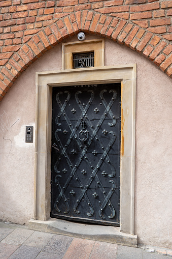 Old doors in the house. Entrance to the building. Forged metal gratings. Poland, Warsaw - July 27, 2023.