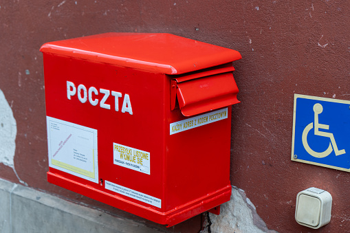Polish red mailbox on the street. Box for letters and correspondence delivery. Warsaw, Poland - July 23, 2023.
