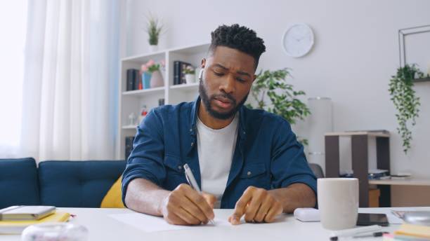 istock Young African American man in headphones taking notes during online lesson, student 1668127169
