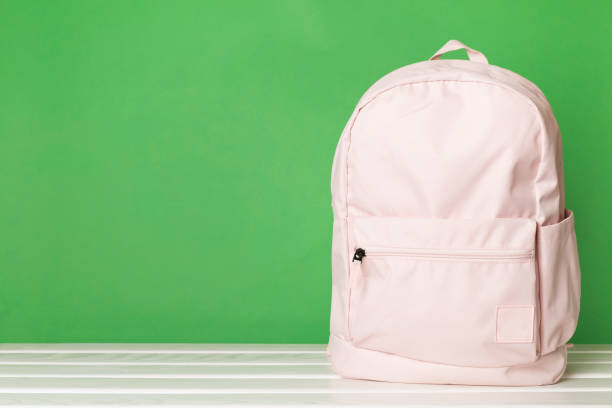 istock Pink school backpack on wooden table 1668138110