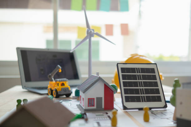 on desk of engineers lay model of house and solar panels to use in planning installation of solar panels to  house in order to get most cost effective energy from installing solar panels. - alternative energy electricity wind turbine team zdjęcia i obrazy z banku zdjęć