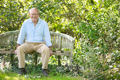 Smiling 65-year-old resting in his garden on a sunny day.