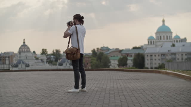 Long haired male traveler photographing cityscape from viewpoint