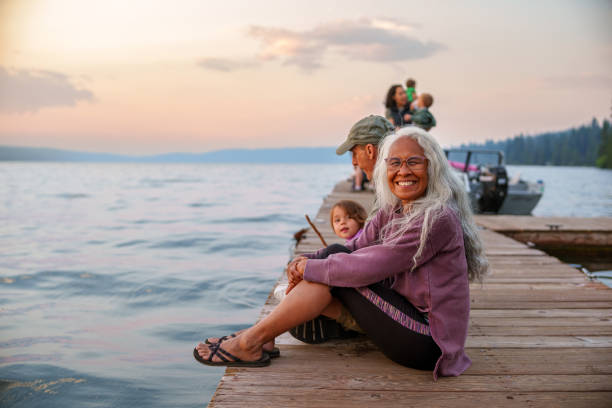 istock Cheerful woman sitting on lakeside dock at sunset 1668284840