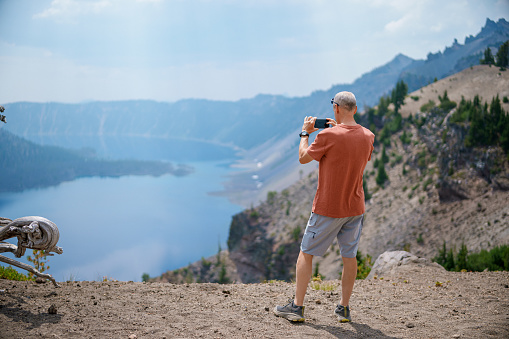 asian photographer standing by a lake looking at view observing