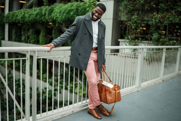 Young man laughs, holding duffel bag outside airport