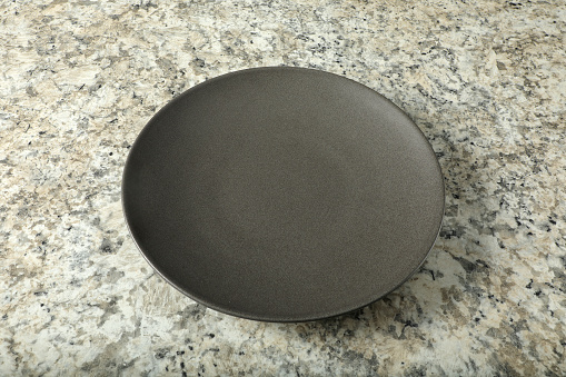 Single empty black plate on table