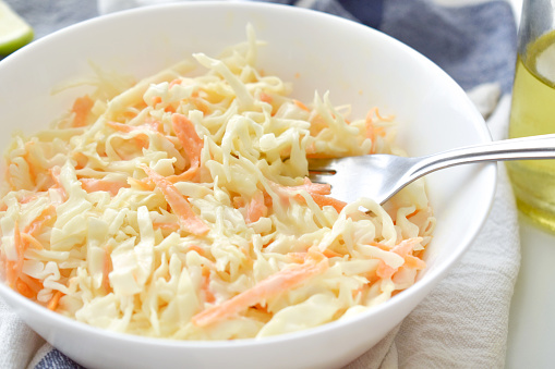 Coleslaw salad with carrot and cabbage in a white bowl.  Healthy and dietary food.