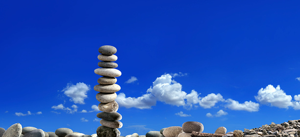 Three stones stacked on a bed of algae overlooking the rocky bay.