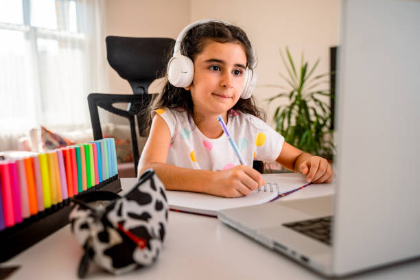 istock Happy school kid in trendy white headphones studying online 1668317821