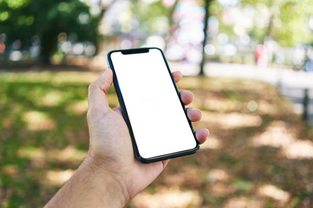 istock Man holding smartphone showing white blank screen at park 1668351780
