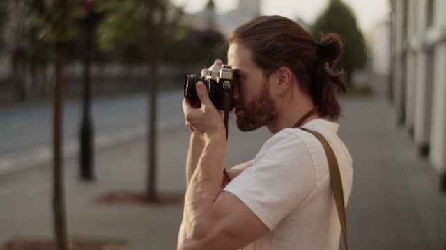 Male photographer taking photos of town on vintage camera