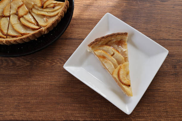 Apple tart on a square plate on a wooden table.