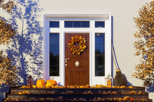Front Door Of House With Halloween Decoration. Hanging Wreath On The Door, Fallen Leaves And Pumpkins On The Doorstep