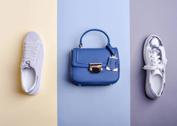 istock Trendy royal blue leather top-handle bag and two different shoes: white-silver sneaker with a cracked effect and pastel perforated leather sneaker on a two-tone background. Fashion blogger content. 1668468113