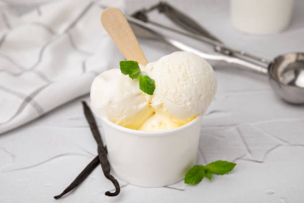 istock Delicious ice cream with mint and vanilla pods on white textured table, closeup 1668536102