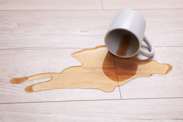 istock White mug with spilled liquid on wooden floor 1668537161