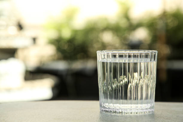 istock Glass of fresh water on light grey table outdoors, closeup. Space for text 1668538208