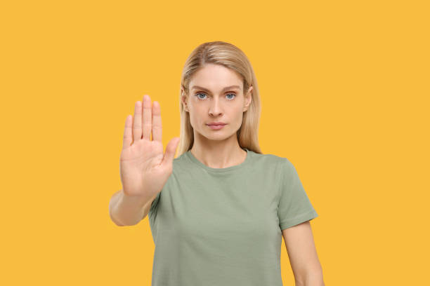 istock Woman showing stop gesture on yellow background 1668576479