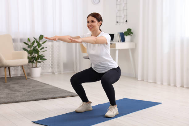 istock Morning exercise. Happy woman squatting at home 1668592409