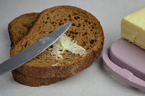 butter is spread on dark bread and a knife is lying
