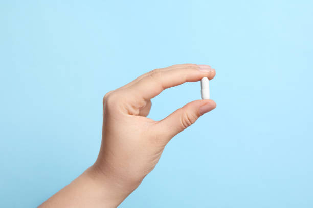 istock Woman holding pill on light blue background, closeup 1668592976