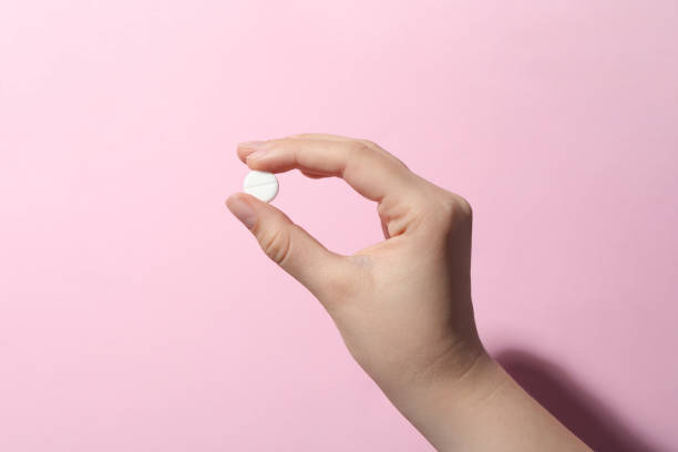 istock Woman holding pill on pink background, closeup 1668593496
