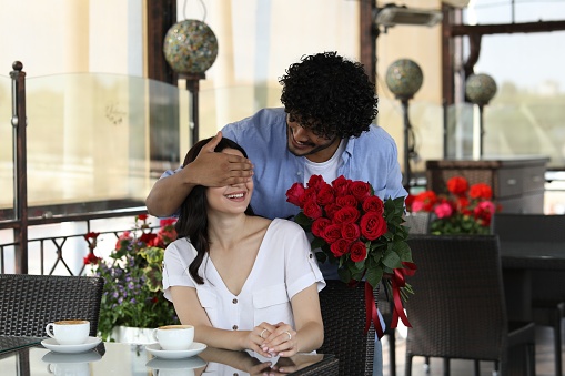 International dating. Handsome man presenting roses to his girlfriend in restaurant