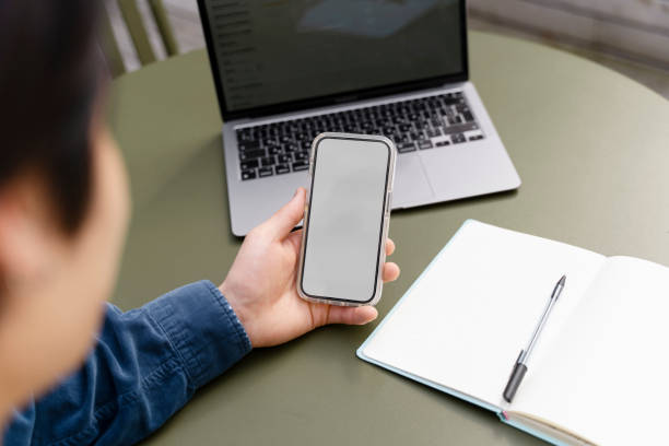 istock Man holding mobile phone with blank, gray screen. Businessman working at workplace 1668667431