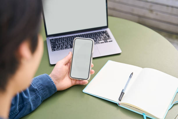 Man hand holding smartphone using mobile app shopping online, looking at blank display. Mockup