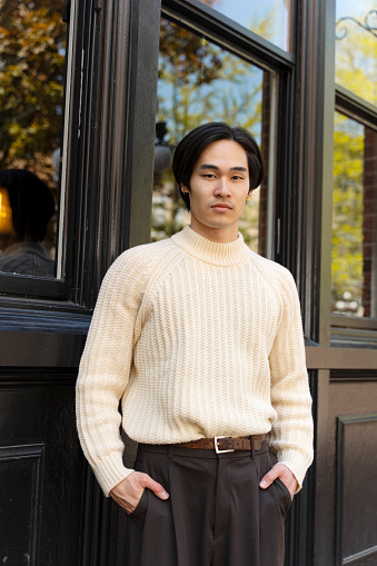 Portrait of attractive asian businessman standing outdoors, looking at camera. Japanese male model in stylish casual clothes posing for picture on university campus