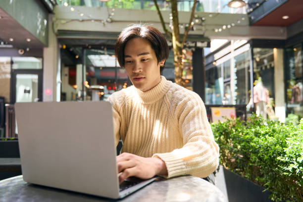 istock Confident asian man author typing laptop computer keyboard, sitting outdoor cafe 1668668015