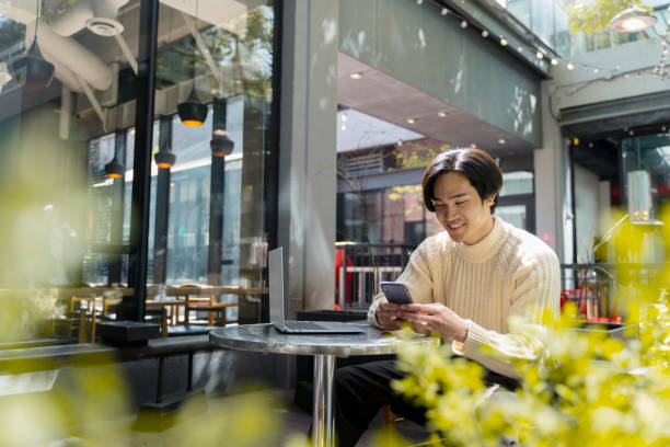istock Smiling, handsome asian manager working using smartphone, online browsing in modern cafe remote work 1668668143