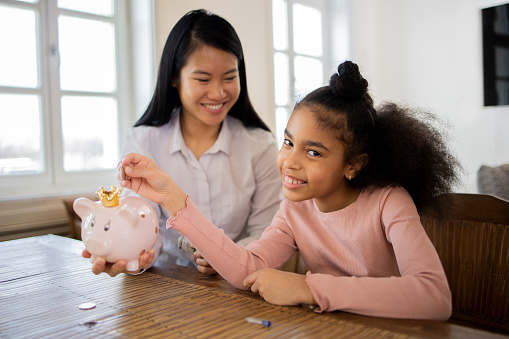 Young woman is teaching the girl good savings habits